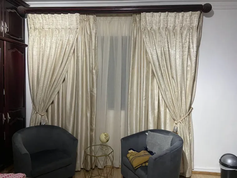 Cream pinch-pleat curtains with tie-backs over sheers in a Cape Town lounge