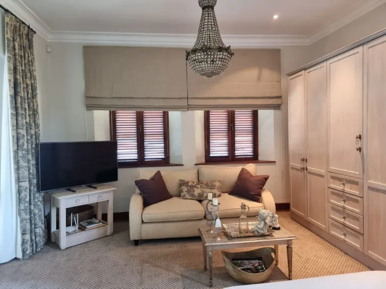 Natural woven roman blind above plantation shutters in a Cape Town lounge