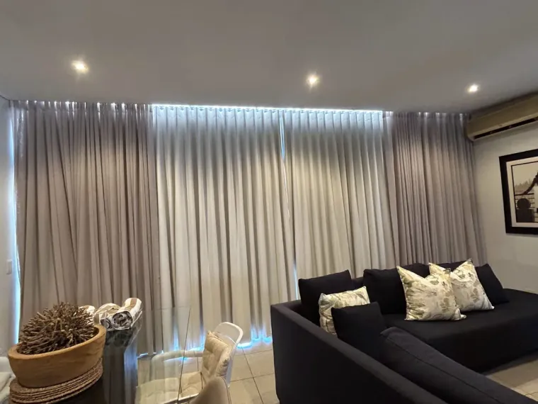 Taupe wave-pleat curtains with LED pelmet lighting in a Cape Town lounge