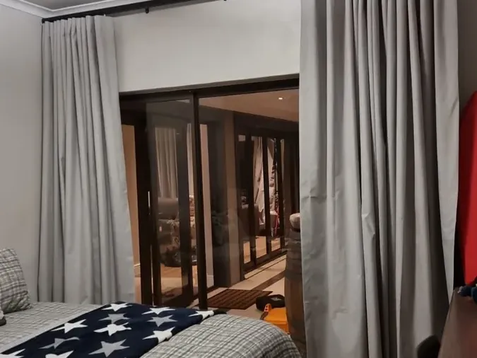 Light grey curtains on a black pole at a sliding door in a Cape Town bedroom
