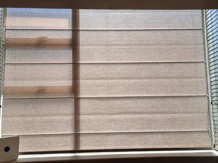 Natural woven roman blind flanked by white venetian blinds in a Cape Town bay window