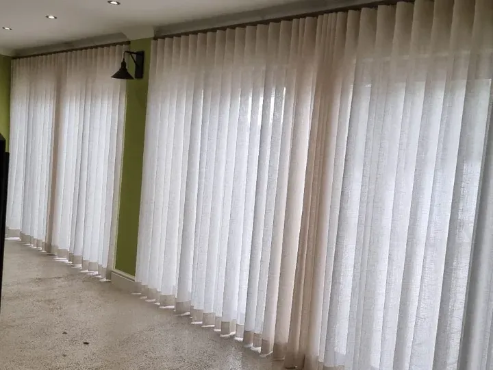 White sheer curtains across a wall of windows in a Cape Town room