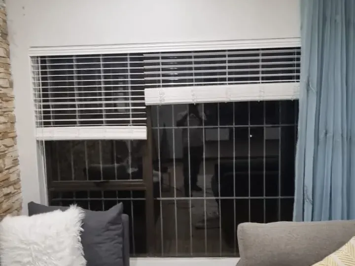 White venetian blinds with a teal curtain panel in a Cape Town lounge