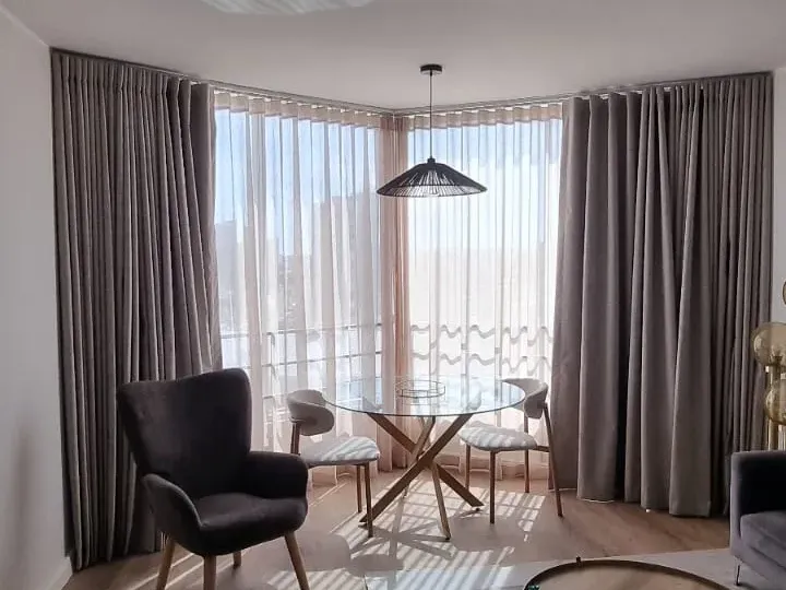 Grey curtains layered over sheers on a bay window in a Sea Point lounge, Cape Town